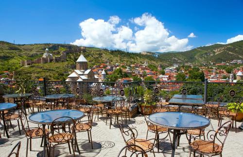 a group of tables and chairs on a balcony with a view at Hotel Kopala in Tbilisi City