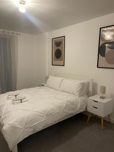 een slaapkamer met een wit bed en een nachtkastje bij Lux One Bedroom Apartment in Barking