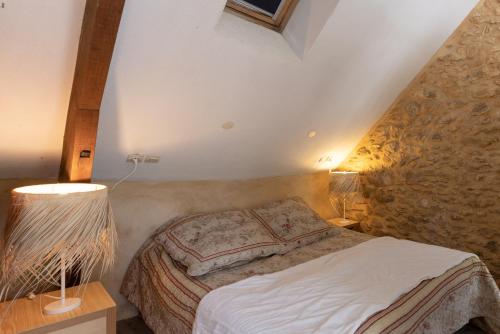 a bedroom with a bed and a stone wall at Domaine Les Maurelles in Milhac