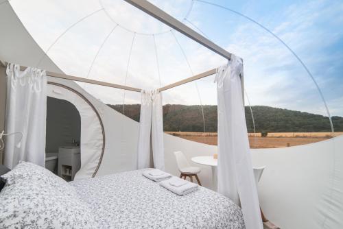 a bedroom with a bed and a table with a view at Bulle à la Belle étoile in Clécy