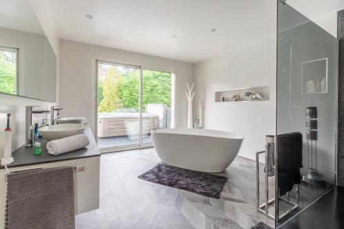 une salle de bain avec une grande baignoire et deux lavabos dans l'établissement Sky view cinema, piscine, Spa, à Ceyrat