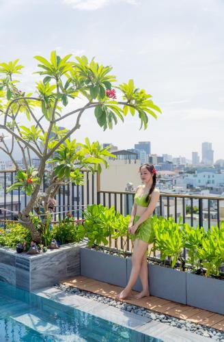 a woman in a green dress standing next to a swimming pool at Seahorse Signature Danang Hotel by Haviland in Da Nang