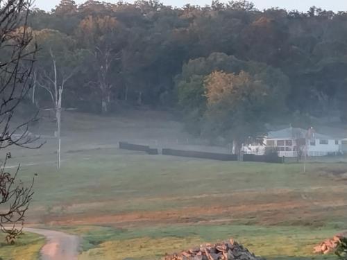 a view of a field with a house in the background at Galah Cottage Stanthorpe in Dalveen