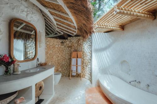 a bathroom with a tub and a sink and a mirror at Bodhi Bingin in Uluwatu