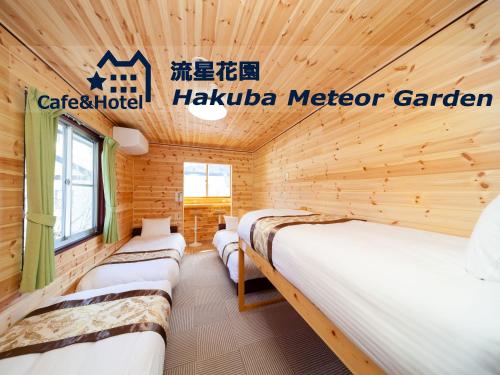 a room with three beds in a wooden cabin at Meteor Garden in Hakuba