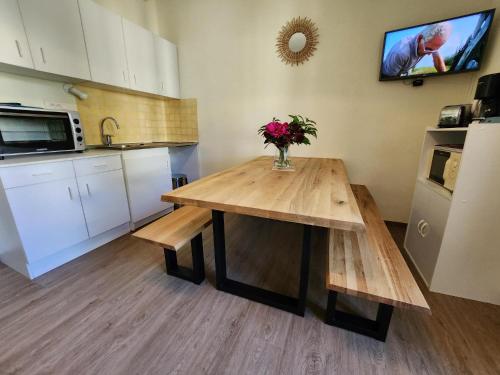 a kitchen with a wooden table with a vase of flowers on it at Gîte Jonquille, 2 à 8 personnes avec salle de jeux et SPA dans la résidence in Ventron