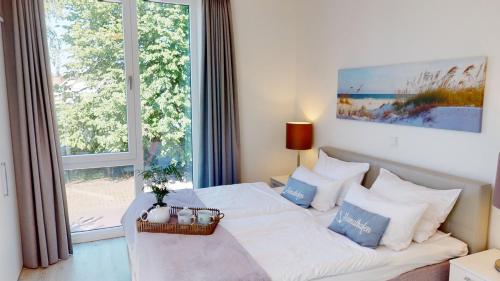 ein Schlafzimmer mit einem Bett und einem großen Fenster in der Unterkunft Südkap C-01 in Pelzerhaken