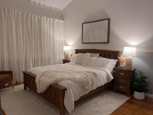 a bedroom with a large bed with two night stands and two lamps at Hideaway Haven in Mudgee