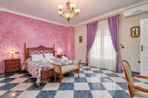 a bedroom with pink walls and a bed and a chair at Villa Soraida in Ítrabo