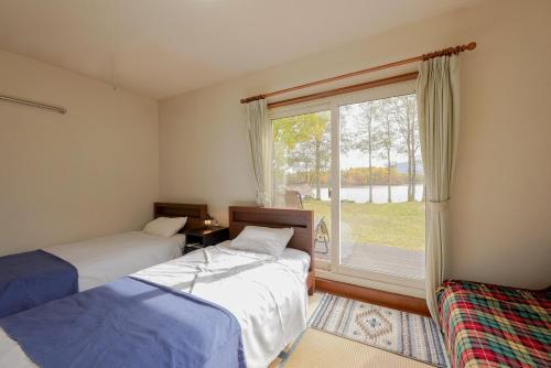 two beds in a room with a large window at Lakeside Hotels Kuore in Kitashiobara