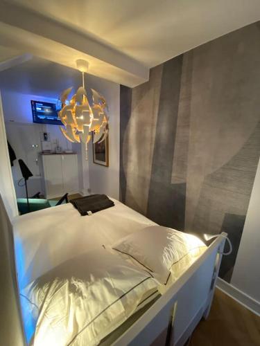 - une chambre avec un lit blanc et un lustre dans l'établissement Rouen galerie 112, à Rouen