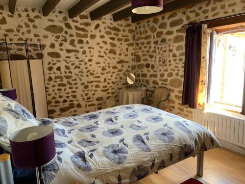 a bedroom with a bed in a room with stone walls at Chez Milo, rural cottage in Roches