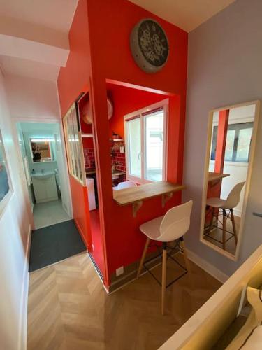 une chambre rouge avec une table et une horloge sur le mur dans l'établissement Rouen galerie 112, à Rouen