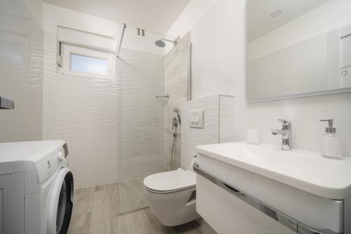 a white bathroom with a toilet and a sink at Pinia Apartments in Vodice