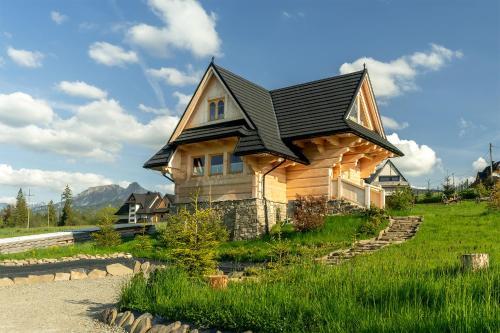 a house with a black roof on top of it at Osada Roztoki - Luxury Chalets in Kościelisko