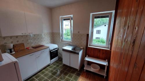 eine Küche mit weißen Geräten und 2 Fenstern in der Unterkunft Apartman SABADIN in Njivice