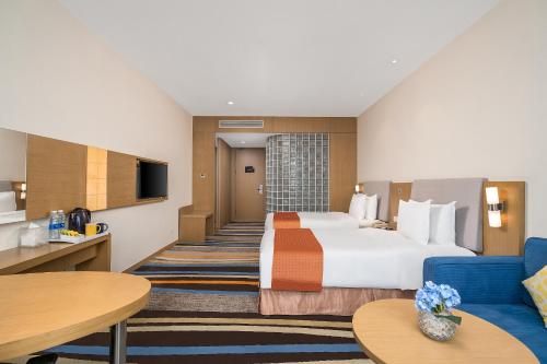Pokój hotelowy z dużym łóżkiem i niebieską kanapą w obiekcie Vyluk Hotel Guangzhou Baiyun International Airport w Guangzhou
