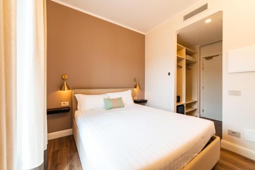 a small bedroom with a white bed and two lamps at Hotel del Conte in Laveno