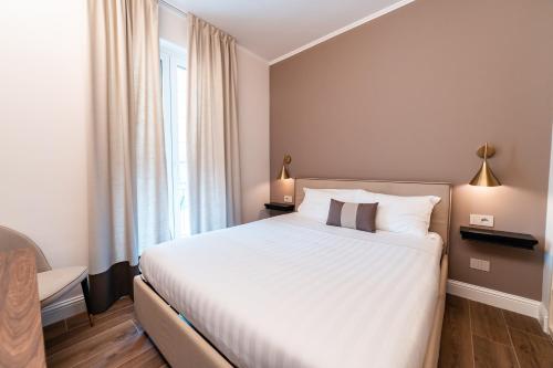 a bedroom with a large white bed and a window at Hotel del Conte in Laveno