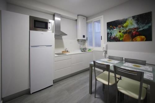a kitchen with a table and a refrigerator and a table and chairs at Calvario 4 in Vigo