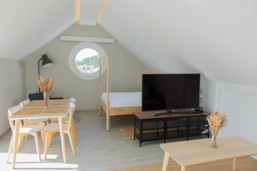 ein Wohnzimmer mit einem TV, einem Tisch und einem Bett in der Unterkunft Apartamentos Dunas de Samil in Vigo
