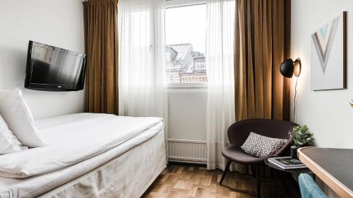 a hotel room with a bed and a tv and a chair at Clarion Hotel Amaranten in Stockholm