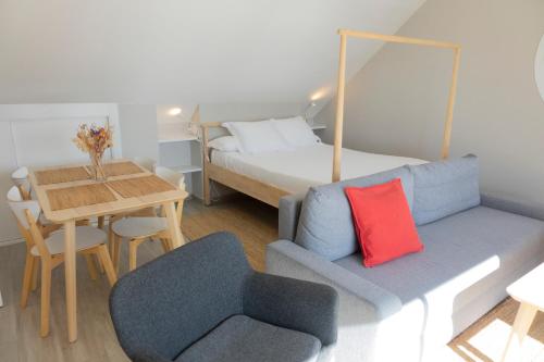 Apartamentos Dunas de Samil في فيغو: غرفة بها أريكة وسرير وطاولة