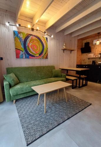 sala de estar con sofá verde y mesa en Apartamenty być morze, en Krynica Morska