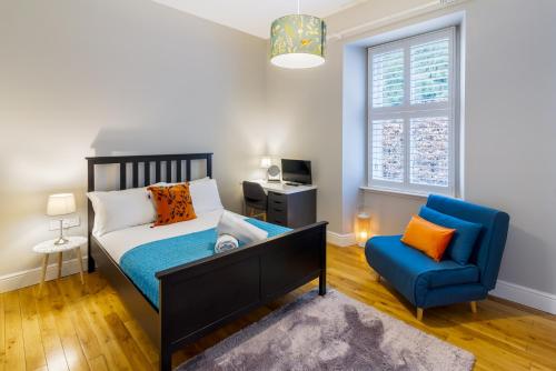 鄧迪的住宿－Westwood Cottage，一间卧室配有一张床和一张蓝色椅子