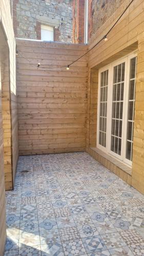 a patio with a wooden wall and a tile floor at Charmante maison à Haybes in Haybes