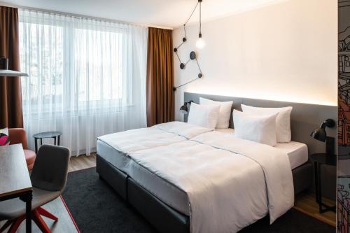ein Hotelzimmer mit einem großen Bett und einem Schreibtisch in der Unterkunft Pentahotel Bremen in Bremen