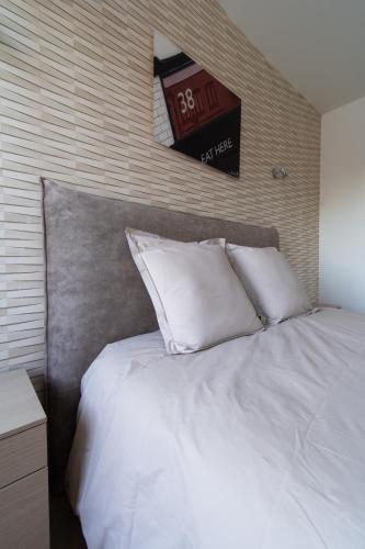 - un lit avec 2 oreillers blancs et une horloge murale dans l'établissement LE MOULIN ROUGE CLAIRMARAIS GITE 