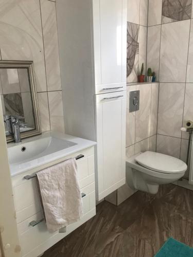 a white bathroom with a toilet and a sink at Viimsis eraldi 36m2-suurune tuba eramajas in Lubja