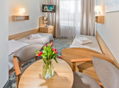 a hotel room with a table with a vase of flowers on it at Piramida Medical SPA in Mrzeżyno