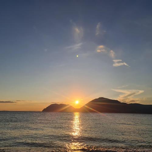 a sunset over the water with mountains in the background at Christina´s Beachside Apartment in Rio