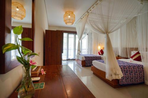 a bedroom with two beds and a canopy bed at Pertiwi Resort & Spa in Ubud