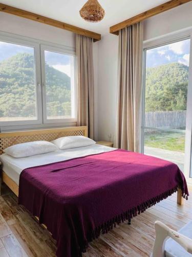 a bedroom with a purple bed with two windows at Villa Kuzyaka; 3 odalı, havuzlu, korunaklı in Fethiye