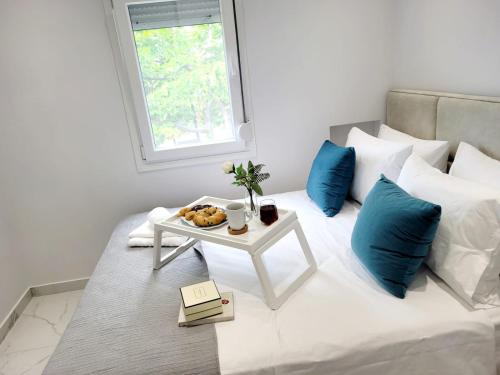 a white bed with a table with a tray of food on it at Astre&Jeanne suites in Sozopoli