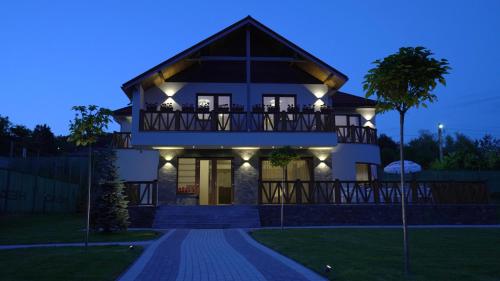 een groot huis met 's nachts verlichting bij Pensiunea Magic in Băile Govora