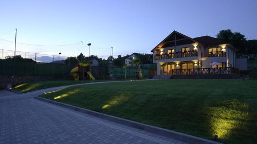 a house with a lawn in front of a house at Pensiunea Magic in Băile Govora