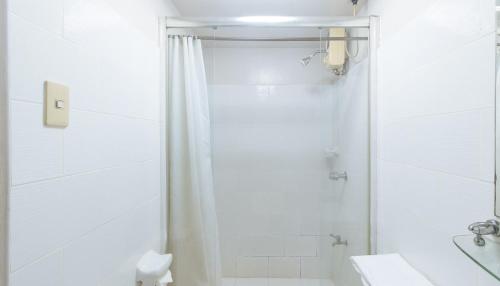 La salle de bains blanche est pourvue d'une douche et de toilettes. dans l'établissement El Rico Suite Makati by RedDoorz, à Manille