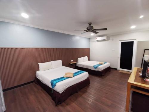 a bedroom with two beds and a ceiling fan at Adina Drive-In Motel Cenang - Managed By Shell Out Resort in Pantai Cenang
