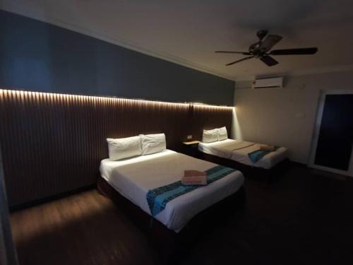 a hotel room with two beds and a ceiling fan at Adina Drive-In Motel Cenang - Managed By Shell Out Resort in Pantai Cenang