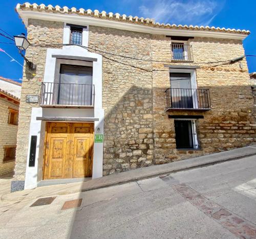 een stenen gebouw met een houten deur en een balkon bij Casa Rural El Americano y disfruta de lo natural in Albentosa