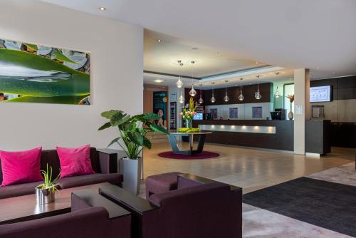 a living room with a couch and a table at Mercure Hotel Düsseldorf Neuss in Neuss