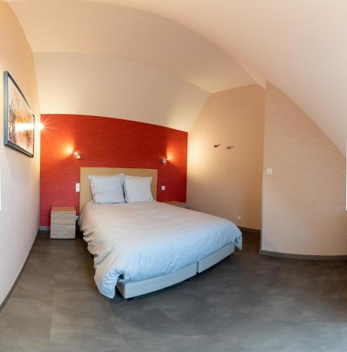 une chambre avec un grand lit avec un mur rouge dans l'établissement Le Moulin Rouge de CLAIRMARAIS 