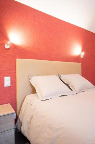 - une chambre avec un mur rouge et un lit blanc dans l'établissement Le Moulin Rouge de CLAIRMARAIS 