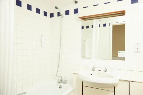 a white bathroom with a sink and a mirror at Bear Hotel by Greene King Inns in Havant