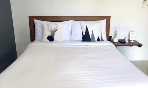 1 cama con sábanas blancas y cabecero de madera en The room Apartment, en Suratthani