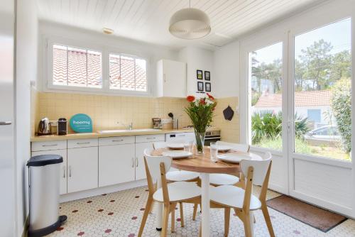 une cuisine avec une table en bois et des armoires blanches dans l'établissement Maison pour 5 entre plage et forêt, à La Barre-de-Monts